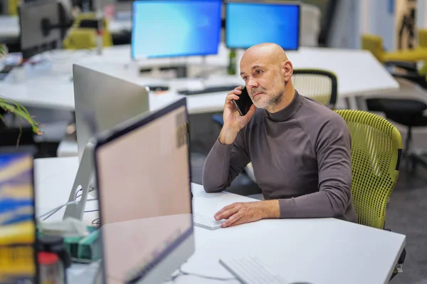 Közepes Felnőtt Üzletember Áll Asztalnál Körülvéve Számítógépekkel Mobiltelefonnal Hivatalban Dolgozó — Stock Fotó