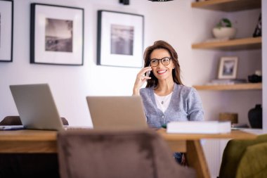 Evde çalışırken göz giysisi ve günlük kıyafetler giyen çekici bir kadın. İş kadını dizüstü bilgisayar kullanıyor ve arama yapıyor. Merkez Ofis.