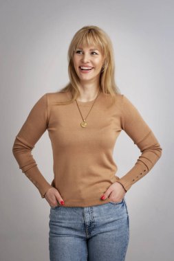 İzole edilmiş arka planda gülümseyen güzel bir kadın. Süveter giyen sarı saçlı kadın. Boşluğu kopyala. 