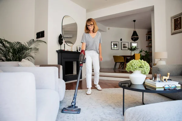 집에서 청소기로 카펫을 여성은 거실에서 일을하고있다 — 스톡 사진