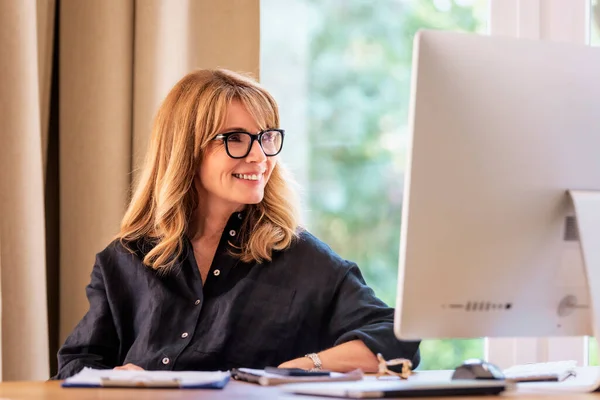 一个中年妇女坐在办公桌前 用电脑工作 有自信的女商人有网络会议和在家工作 总部办公室 — 图库照片