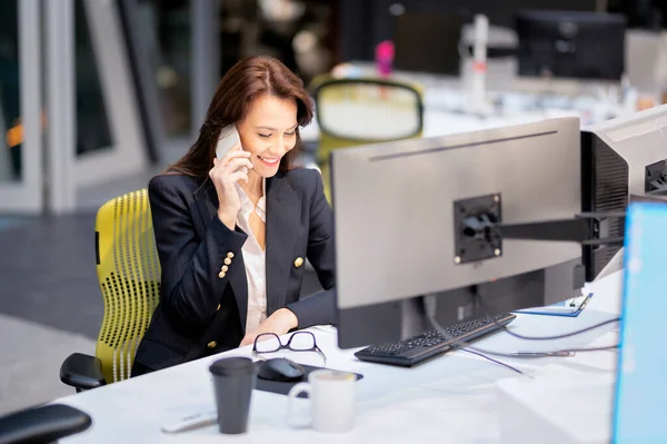 Orta Yaşlı Kadını Bilgisayar Kullanıyor Ofiste Masa Başında Otururken Telefonla Stok Resim