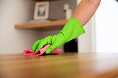 Evdeki yemek masasını silen bir kadının yakın çekimi. Lastik eldiven takan ve evi temizlerken temizlik sıvısı kullanan kendine güvenen bir kadın.. 