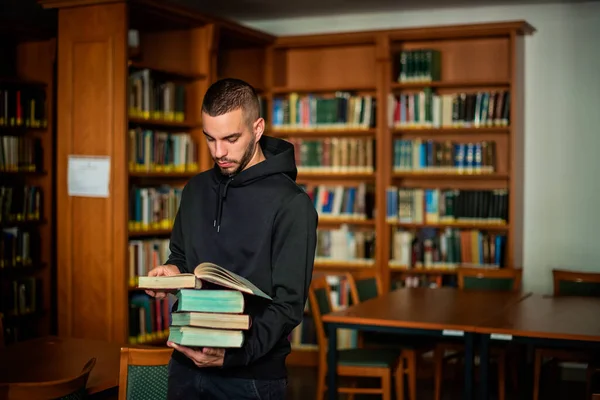 Młody Człowiek Stojący Bibliotece Uniwersyteckiej Trzymający Książki Ręku Przystojny Mężczyzna — Zdjęcie stockowe
