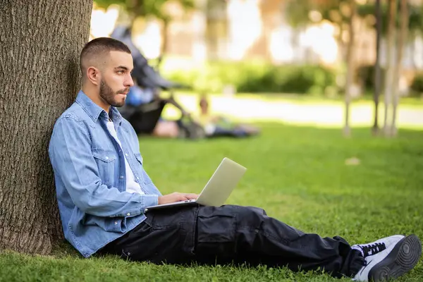 옥외에서 공부하거나 일하기 노트북을 사용하는 젊은이 캐주얼 공원에서 잔디에 온라인 — 스톡 사진