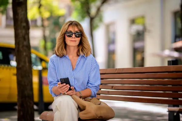 Aantrekkelijke Vrouw Met Blond Haar Zit Een Bankje Straat Gebruikt — Stockfoto