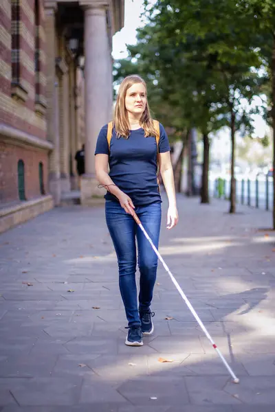 路上で歩いている白い杖を持つ盲目の女性の肖像画 視覚障害のある女性がカジュアルな服を着て 道を渡るために杖を使った 全長ショット — ストック写真