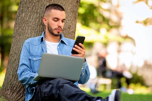 옥외에서 공부하거나 일하기 노트북을 사용하는 젊은이 캐주얼 공원에서 잔디에 메시지 로열티 프리 스톡 사진