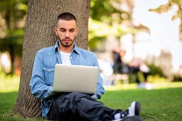옥외에서 공부하거나 일하기 노트북을 사용하는 젊은이 캐주얼 공원에서 잔디에 — 스톡 사진