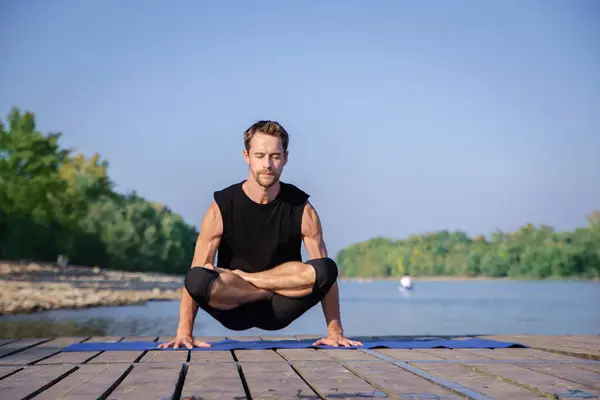 全长的高加索男子在一个又一个湖边的码头上练习瑜伽 — 图库照片