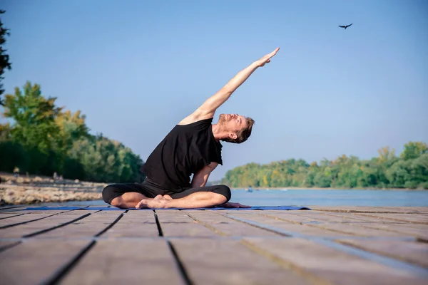 全长的高加索男子在一个又一个湖边的码头上练习瑜伽 — 图库照片
