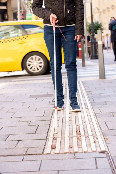 路上で歩いている白い杖を持つ盲目の女性の足のクローズアップ 道を歩くために彼女の杖を使用して視覚障害のある女性 — ストック写真