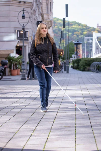 路上で歩いている白い杖を持つ盲目の女性の肖像画 視覚障害のある女性がカジュアルな服を着て 彼女の杖を使って通りを歩いている 全長ショット — ストック写真