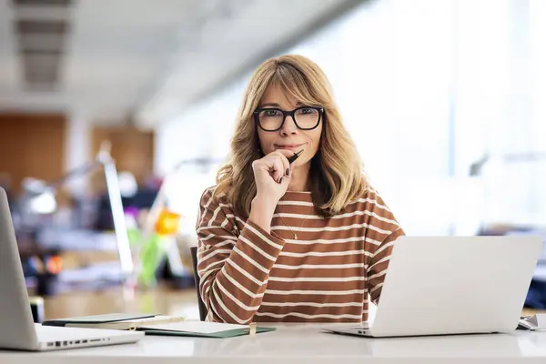 オフィスに座って仕事のためにラップトップを使用するビジネスマン メガネとカジュアルな服を着ている自信のあるプロフェッショナル女性 — ストック写真