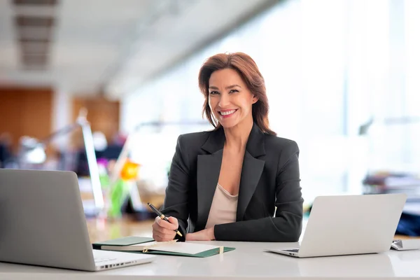 オフィスで机の上に座っている中年女性 仕事のためにラップトップを使用して自信を持ったプロの女性 コピースペース — ストック写真
