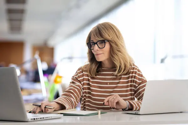 Kadını Ofiste Oturuyor Için Dizüstü Bilgisayar Kullanıyor Gözlüklü Günlük Kıyafetler Telifsiz Stok Fotoğraflar