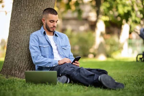 옥외에서 공부하거나 일하기 노트북과 스마트 사용하는 젊은이 캐주얼 공원에서 잔디에 — 스톡 사진