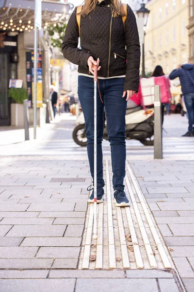 街の道路を横断する白い杖を持つ盲目の女性のクローズアップ カジュアルな服を着た視覚障害の女性と 彼女の杖を使って通りを横断する ロイヤリティフリーのストック画像