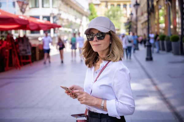 Close-up of an attractive woman wearing smart clothes and sunglasses while walking in a city and speaking on her mobile phone.