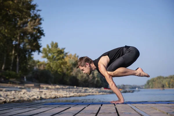 Middle aged man practicing yoga outdoor. Caucasian man using yoga mat and holding plank pose.