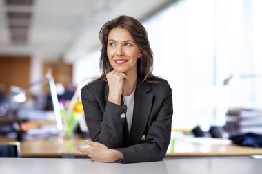 Ofiste otururken siyah ceket giyen çekici bir iş kadınının portresi..