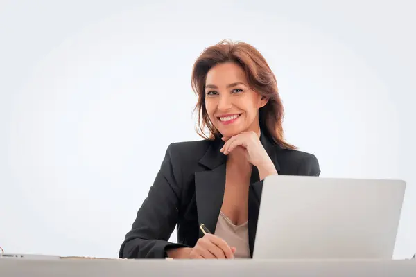 孤立した背景から机の上に座っている中年の実業家 仕事のためにラップトップを使用して自信のあるプロフェッショナル女性 コピースペース ストックフォト