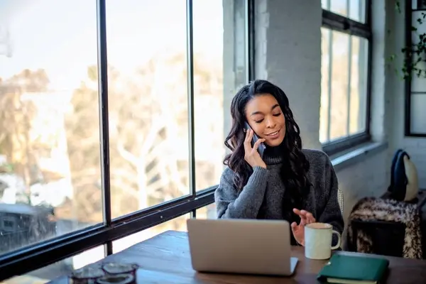 Afroamerykanka Siedząca Przy Stole Przy Oknie Mówiąca Przez Smartfona Biuro Obraz Stockowy