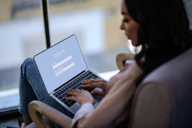 Laptop klavyesinde yazı yazan Afro-Amerikan bir kadının yan görüntüsü. E-posta hesabına giriş yapıyor. Kafede dizüstü bilgisayarla çalışan serbest çalışan biri..