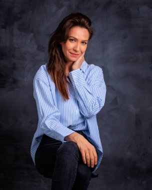 Esmer bir kadının stüdyo portresi izole edilmiş arka planda oturuyor. Gömlek giyen ve kameraya bakan çekici bir kadın. Boşluğu kopyala. 