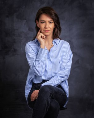 Esmer bir kadının stüdyo portresi izole edilmiş arka planda oturuyor. Gömlek giyen ve kameraya bakan çekici bir kadın. Boşluğu kopyala. 