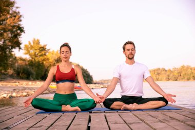 Dışarıda yoga yapan bir çiftin boyu. Lotus poz veren kadın ve erkek..
