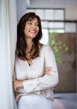 Güzel esmer bir kadının portresi duvarda dikilmiş neşeli bir gülümseme. Orta yaşlı kadın gömlek giyiyor ve başka tarafa bakıyor.. 