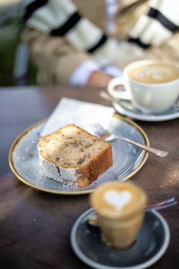 Kafedeki bir kahvenin yakın planında. Cappuccino içen bir kadın ve biraz tatlı. Açık Cafe.