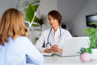 Ofiste çalışan ve semptomlarını açıklayıp danışmanlık yaparken hastayı dinleyen kadın doktor..