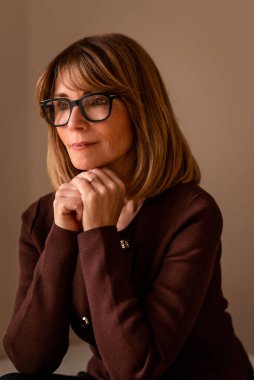 Gülümseyen sarı saçlı kadın duvarın önünde rahatlıyor ve beyaz kadın gibi giyiniyor.. 