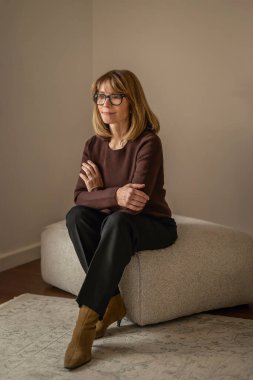 Gülümseyen sarı saçlı kadın duvarın önünde rahatlıyor ve düşünceli görünüyor.. 