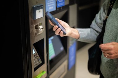 Alışveriş merkezinde park ücretini telefonla ödeyen bir kadın. Temassız ödeme 