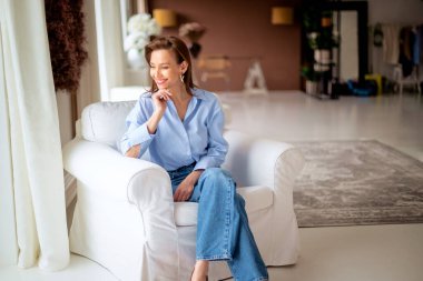 Güzel bir kadın evde rahatlatıcı bir günün tadını çıkarıyor. Orta yaşlı kadın rahat koltuğunda otururken ışıl ışıl gülümsüyor.. 