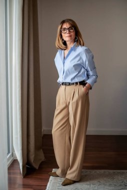 Modern oturma odasında pencereli gülümseyen kadın portresi. Sarışın, gülümseyen çekici bir kadın. Tam boy çekim.  