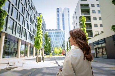 Kendine güvenen bir iş kadını elinde dizüstü bilgisayarla iş bölgesinde dolaşıyor. İş kıyafeti giyen orta yaşlı profesyonel bir kadın.. 