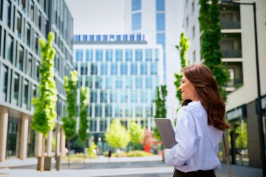 İş yerindeki ofise yürüyen kendine güvenen bir iş kadını. Profesyonel bir kadın cep telefonunu kullanıyor ve iş görüşmesi yapıyor. Esmer, iş kıyafeti giyen bir kadın.. 
