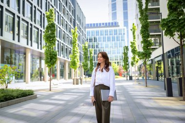 İş yerindeki ofise yürüyen kendine güvenen bir iş kadını. Profesyonel bir kadın cep telefonunu kullanıyor ve iş görüşmesi yapıyor. Esmer, iş kıyafeti giyen bir kadın.. 