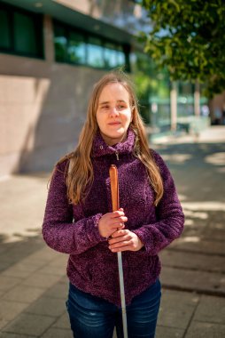 Görme engelli bir kadın, kız arkadaşıyla şehirde yürüyor. Görme engelli arkadaşına yardım eden olgun beyaz bir kadın..  