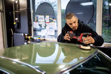 Tamirci araba tamirhanesinde araba cilalama makinesiyle cilalıyor.. 