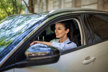 Gülümseyen orta yaşlı kadın sürücü arabasında oturuyor ve eve gidiyor. Sıradan kıyafetler giyen çekici bir kadın.. 