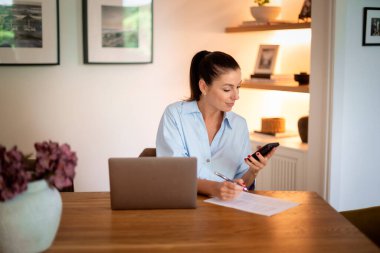 Mutlu kadın akıllı telefon kullanıyor ve evden çalışıyor. Kendine güvenen bir kadın dizüstü bilgisayarının önünde oturuyor ve mesaj atıyor. Merkez Ofis.