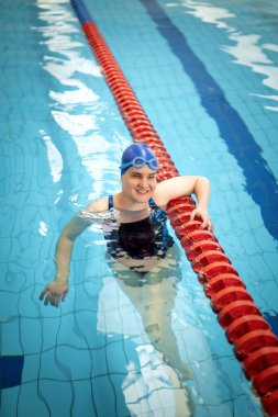 Kapalı havuzda yüzen görme engelli bir kadın. Mayo ve yüzme şapkası takan kendinden emin bir kadın.. 