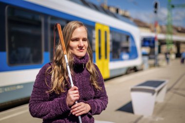 Beyaz bastonlu kör kadın portresi. Şehrin dışındaki tren istasyonunda bankta oturuyor. Treni bekleyen görme engelli bir kadın. Günlük kıyafetler.. 
