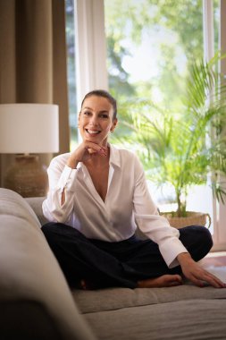 Güzel, orta yaşlı bir kadının rahat koltukta oturup kameraya bakıp gülümsediği ve hayal kurduğu uzun bir çekim.