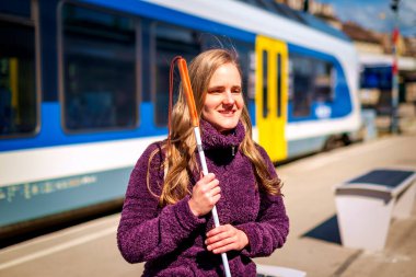 Beyaz bastonlu görme engelli bir kadın tren istasyonunda oturuyor ve birini bekliyor.. 